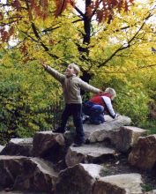 Kinder auf Steinhaufen, ein Kind wirft fröhlich die Arme in die Luft