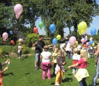 Kinder auf einer Wiese mit Luftballons